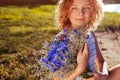 Outdoor portrait of beautiful young woman with red curly hair holding bouquet of flowers. Natural cosmetics Royalty Free Stock Photo