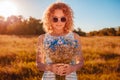 Outdoor portrait of beautiful young woman with red curly hair holding bouquet of flowers. Allergy free Royalty Free Stock Photo