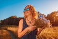 Outdoor portrait of beautiful young woman with red curly hair holding flowers. Summer mood. Royalty Free Stock Photo