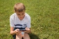 Outdoor portrait of blond boy teenager, male young man texting or using social media on cell phone on nature background Royalty Free Stock Photo