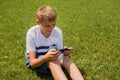 Outdoor portrait of blond boy teenager, male young man texting or using social media on cell phone on nature background Royalty Free Stock Photo