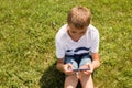 Outdoor portrait of blond boy teenager, male young man texting or using social media on cell phone on nature background Royalty Free Stock Photo