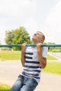 Outdoor portrait of blond boy teenager, young man on brachiating bar at a school yard. Boy doing pull ups. Royalty Free Stock Photo