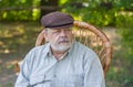 Portrait of Caucasian senior man sitting in a chair in summer park