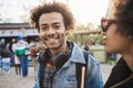 Outdoor portrait of charming african-american man walking with friend in park, wearing denim clothes and headphones over Royalty Free Stock Photo