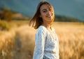 Outdoor portrait of charming happy woman standing at wheat field in golden sun lights Royalty Free Stock Photo