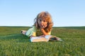 Outdoor portrait of a cute little boy reading a book. Schoolboy with a book having a rest outdoor. Royalty Free Stock Photo