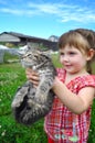 Outdoor portrait of a cute little girl with small kitten, girl playing with cat on natural background