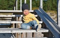 Outdoor portrait of cute little toddler boy sitting on a wooden stairs in Baltic dunes Royalty Free Stock Photo