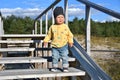 Outdoor portrait of cute little toddler boy sitting on a wooden stairs in Baltic dunes