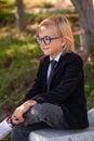 Outdoor portrait of Fashionable Schoolboy with glasses, school uniform, blonde boy with long hair Royalty Free Stock Photo