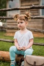 Outdoor portrait of a girl sitting on the grass near the fence.Summer in the village. beautiful baby girl on a wooden bench. Royalty Free Stock Photo