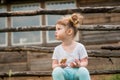 Outdoor portrait of a girl sitting on the grass near the fence.Summer in the village. beautiful baby girl on a wooden bench. Royalty Free Stock Photo