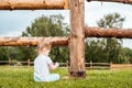 Outdoor portrait of a girl sitting on the grass near the fence.Summer in the village. beautiful baby girl on a wooden bench. Royalty Free Stock Photo