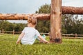 Outdoor portrait of a girl sitting on the grass near the fence.Summer in the village. beautiful baby girl on a wooden bench. Royalty Free Stock Photo