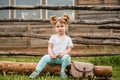 outdoor portrait of a girl sitting on the grass near the fence.Summer in the village. beautiful baby girl on a wooden Royalty Free Stock Photo