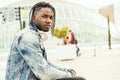 Outdoor portrait of a handsome and attractive young African man with music headphones on the street