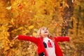 Outdoor portrait of happy blonde child girl in a red jacket holding yellow leaves. Little girl walking in the autumn park or Royalty Free Stock Photo