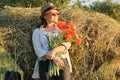 Outdoor portrait of happy mature woman with a bouquet of poppies red flowers