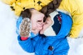 Outdoor portrait Happy mother and baby lying on the snow in wint