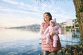 Outdoor portrait of happy young mother with adorable baby girl enjoying nice view of winter lake Geneva Royalty Free Stock Photo