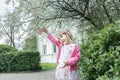 Outdoor portrait of joyful blonde girl at blooming fruit tree and porch background