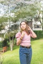 Outdoor portrait of a Latina teenage girl adjusting her straight hair with her hands in pink blouse and jeans Royalty Free Stock Photo