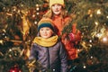 Outdoor portrait of little children next to Christmas tree with lights Royalty Free Stock Photo