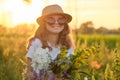 Outdoor portrait of a little girl with flowers on a sunny meadow, golden hour Royalty Free Stock Photo