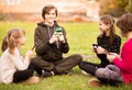 Outdoor portrait of little girl with friends playing with phones outdoor