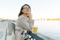 Outdoor portrait of mature smiling woman in glasses with cup of coffee and mobile phone. Woman in the city on the embankment of Royalty Free Stock Photo