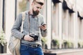 Outdoor portrait of modern young traveler man using smart phone on the street