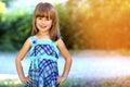 Outdoor portrait of optimistic smiling pretty little girl in blu