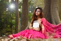 Outdoor portrait of pleased brunette beautiful Indian woman in eyeglasses wearing traditional Indian saree and jewellery, sitting Royalty Free Stock Photo