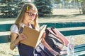 Outdoor portrait of pretty little girl in school uniform glasses, with backpack bottle of water, reading book Royalty Free Stock Photo