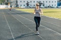 Outdoor portrait of running smiling mature woman in stadium on sunny spring day