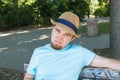 Outdoor portrait of sad young man sitting on bench in park. Sadness and disappointment concept