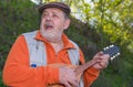 Portrait of senior man playing mandolin while singing Royalty Free Stock Photo