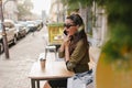 Outdoor portrait of shocked brunette girl in sunglasses talking on phone in autumn morning. Surprised shopaholic woman Royalty Free Stock Photo