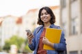 Outdoor Portrait Of Smiling Arab Female Student With Smartphone And Workbooks Royalty Free Stock Photo
