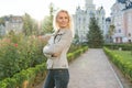 Outdoor portrait of smiling blond woman with curly hair with arms crossed, city street background Royalty Free Stock Photo