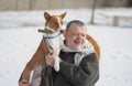 Portrait of smiling Caucasian senior man taking his cute basenji dog on the hands while sitting in a wicker chair Royalty Free Stock Photo