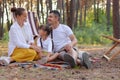 Outdoor portrait of smiling delighted family spending time together in the forest, people wearing casual clothing, sitting on Royalty Free Stock Photo