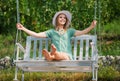 Outdoor portrait of a smiling happy girl. Young sexy woman is swinging on a swing in summer park garden. Sensual blonde Royalty Free Stock Photo