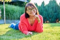 Outdoor portrait of smiling middle aged woman lying on grass Royalty Free Stock Photo