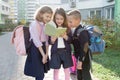 Outdoor portrait of smiling schoolchildren in elementary school. Group of kids with backpacks are having fun, talking, reading a Royalty Free Stock Photo