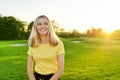 Outdoor portrait of smiling teenage girl 16, 17 years old in yellow T-shirt, on green sunny lawn Royalty Free Stock Photo