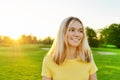 Outdoor portrait of smiling teenage girl 16, 17 years old in yellow T-shirt, on green sunny lawn Royalty Free Stock Photo