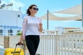 Outdoor portrait of tourist woman with suitcase at hotel sea spa resort, copy space Royalty Free Stock Photo