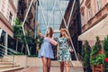 Outdoor portrait of two young beautiful women walking on city street. Best friends hanging, having fun